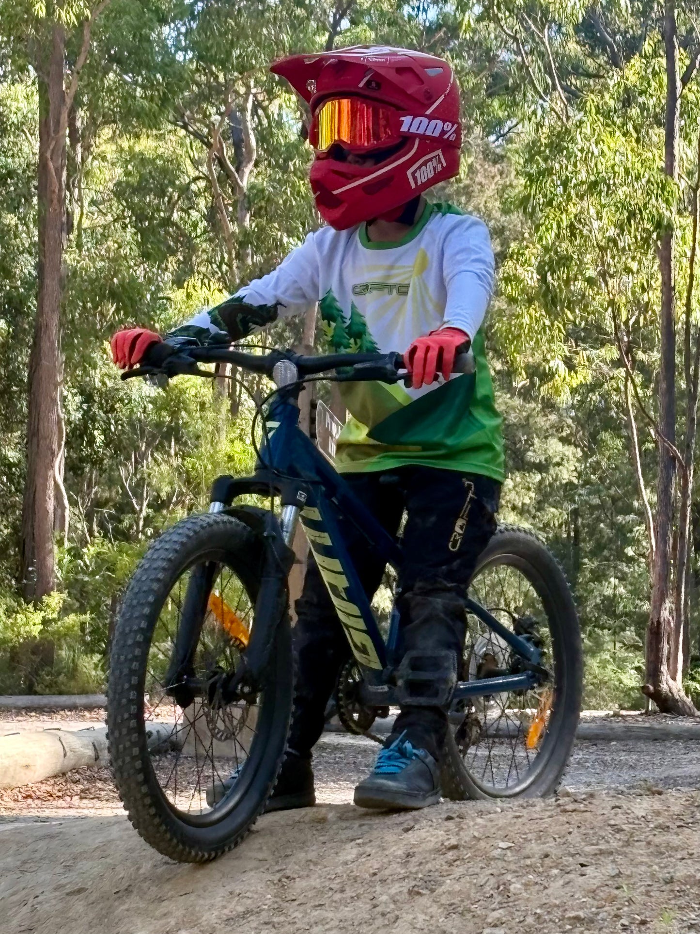 child on a bike wearing long sleeve crofto mtb jersey and red helmet
