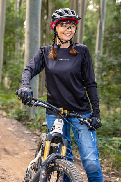 A female rider wearing a black CROFTO Enduro mountain bike jersey suitable for trail riding, enduro racing and all-mountain adventures.