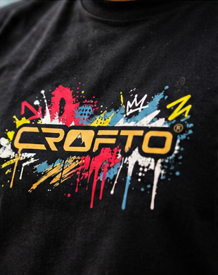 Close-up of CROFTO Paintstorm Tee front chest graphic with colourful paint splatter artwork and CROFTO logo