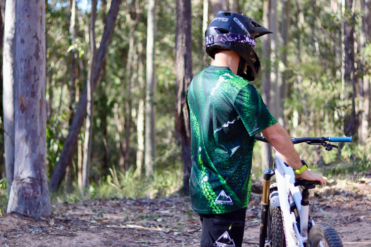 Mountain bike rider wearing a CROFTO Viper green scale mountain bike jersey, breathable MTB riding jersey for trail and enduro riding.