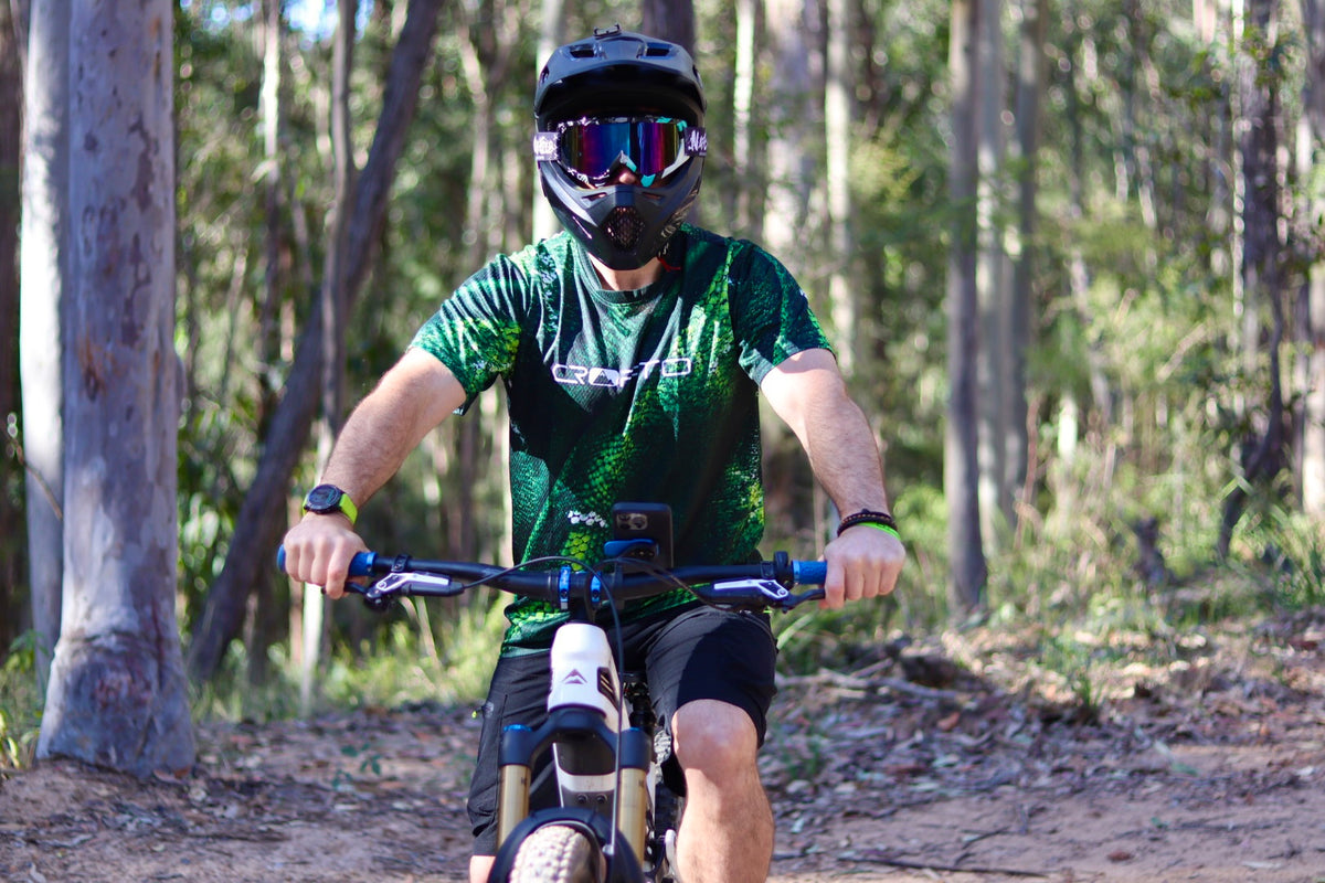 Man sitting on a mountain bike in a forest wearing a CROFTO Viper MTB jersey in green