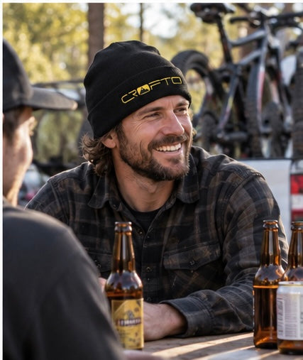 Mountain biker wearing a black CROFTO beanie while catching up with friends after a ride at the trailhead.