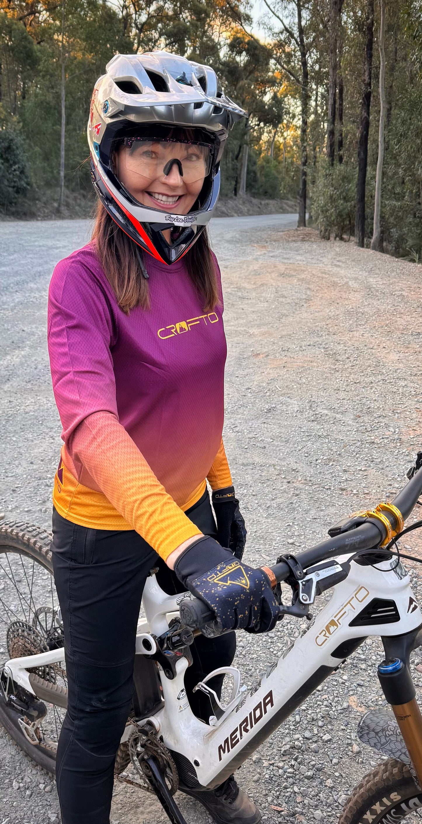 Person wearing a helmet and cycling outfit with a bicycle on a gravel path.