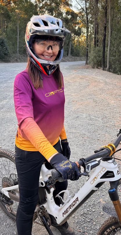 Person wearing a helmet and cycling outfit with a bicycle on a gravel path.