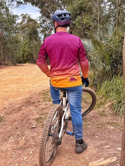 Person on a mountain bike wearing a colorful shirt and helmet in a forest setting