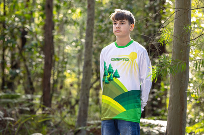 Boy standing in the forest on a berm wearing a CROFTO Hacklberg MTB jersey 
