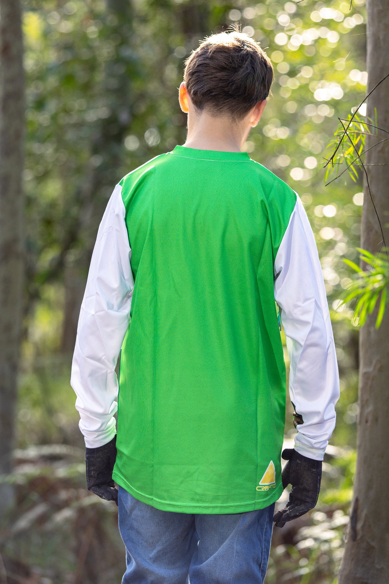 Boy standing in the forest wearing a CROFTO Hacklberg MTB jersey 