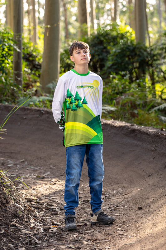 Boy standing in the forest on a berm wearing a CROFTO Hacklberg MTB jersey 