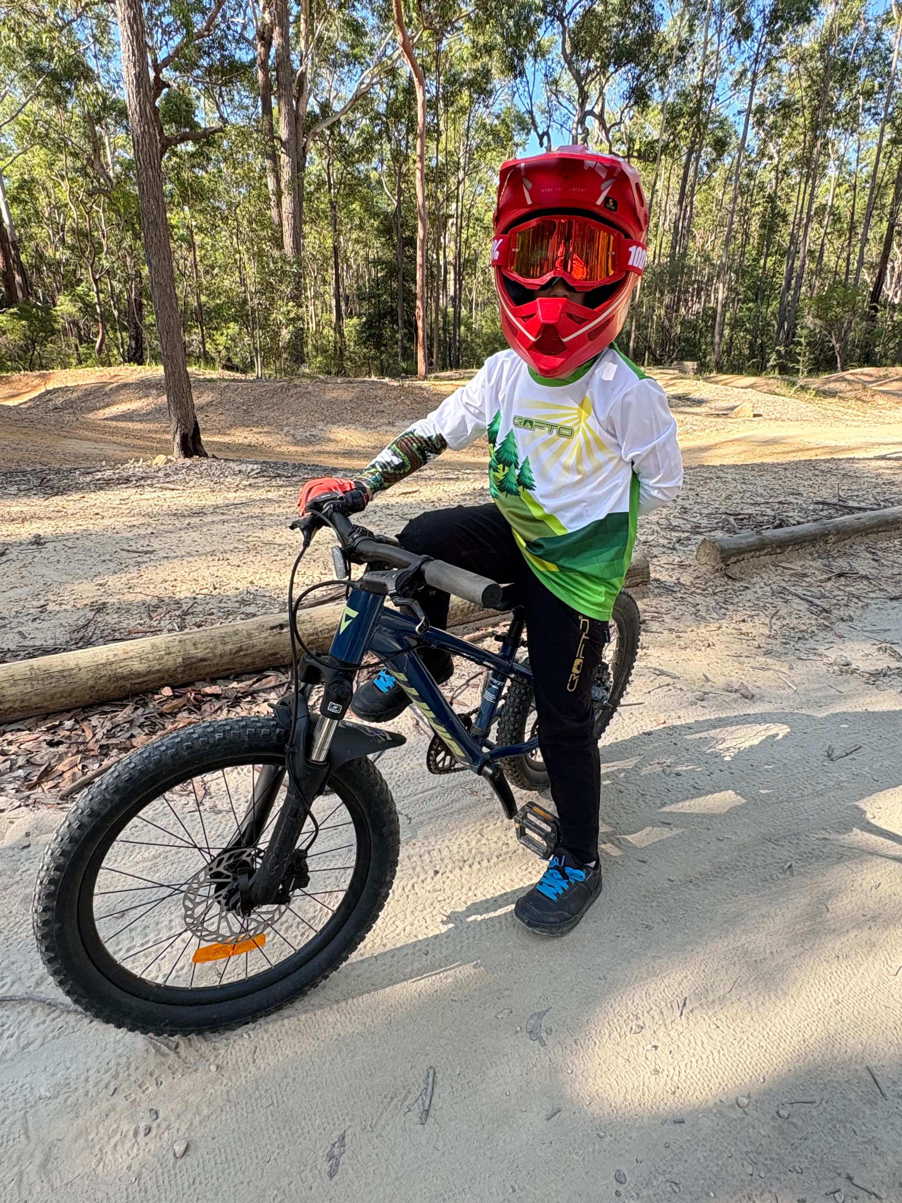 Child on a bicycle wearing a helmet and goggles in a forest setting
