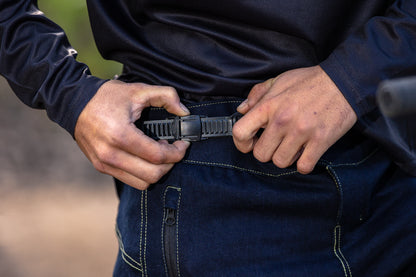 A close up of a mountain biker adjusting the waist ratchet of CROFTO denim MTB Jorts