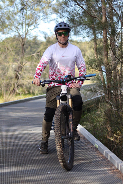 A man sitting on a mountain bike next to the forest wearing a CROFTO Mont Blanc Long Sleeve MTB jersey and dark green Amaroo pants