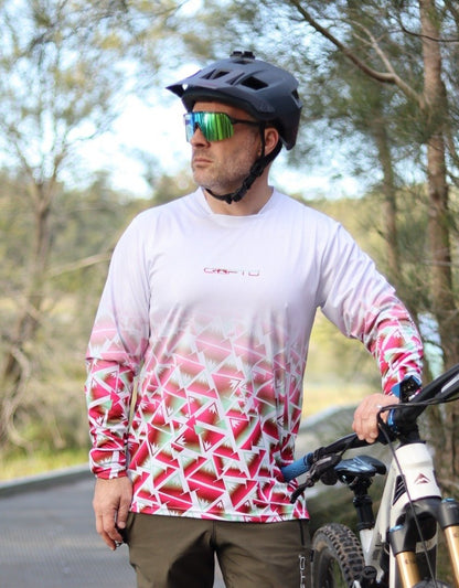 A close up of a man standing next to a mountain bike next to the forest wearing a CROFTO Mont Blanc Long Sleeve MTB jersey and dark green Amaroo pants