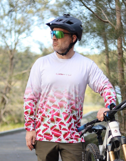 A close up of a man standing next to a mountain bike next to the forest wearing a CROFTO Mont Blanc Long Sleeve MTB jersey and dark green Amaroo pants