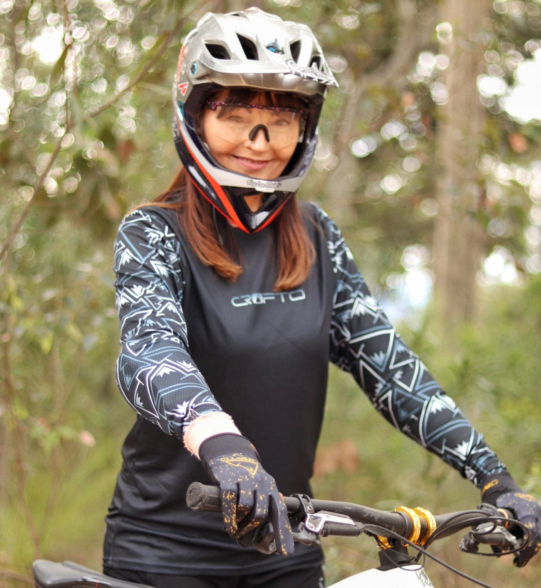 Person on a mountain bike wearing a helmet and gloves in a forest setting