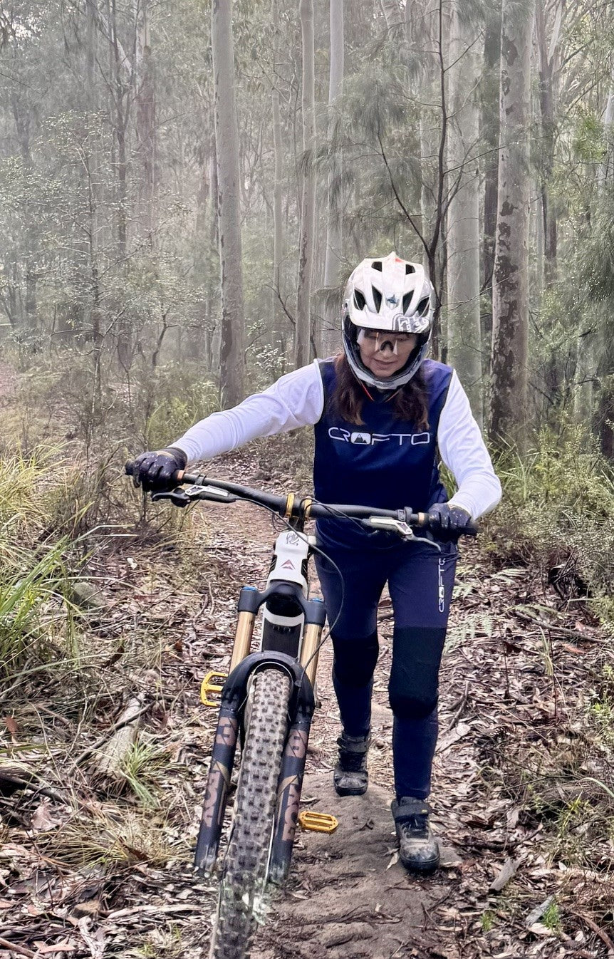 Woman pushing a mountain bike in forest in crofto amaroo pants