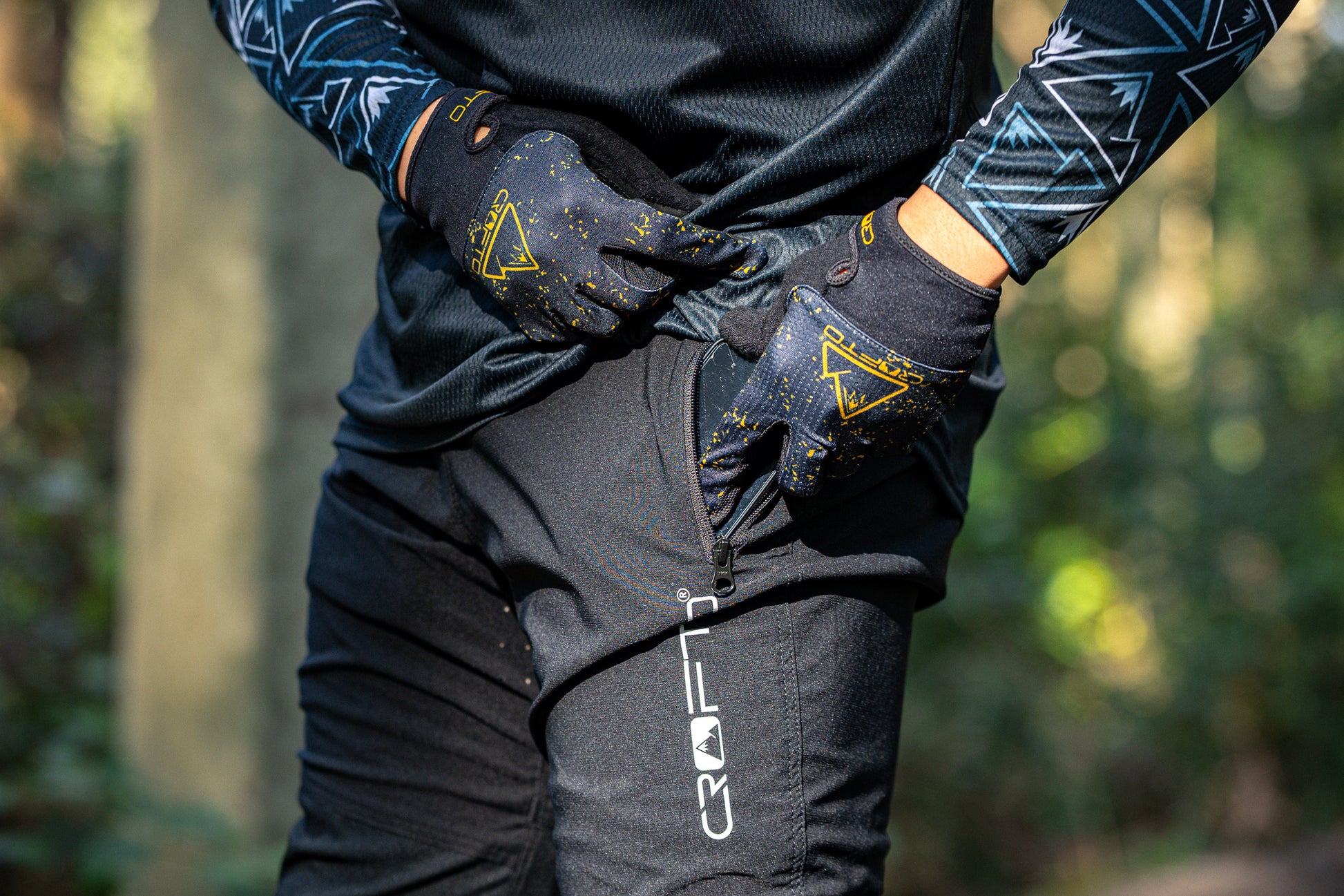 Close up of a person wearing crofto amaroo mountain bike pants putting a phone in the side pocket
