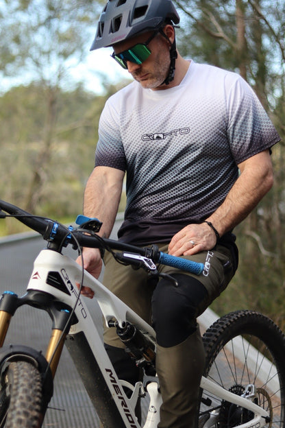 A man sitting on a mountain bike near the Australian forest wearing a navy helmet and CROFTO Carbon Classic mountain bike jersey and dark green Amaroo MTB pants