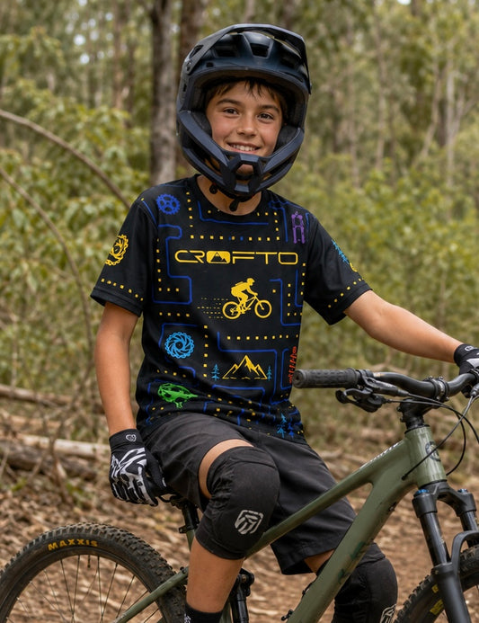 Boy sitting on a mountain bike wearing CROFTO trail maze mtb jersey.
