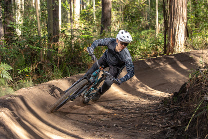 A mountain bike rider on a berm wearing CROFTO mozaic jersey and Amaroo pants in black