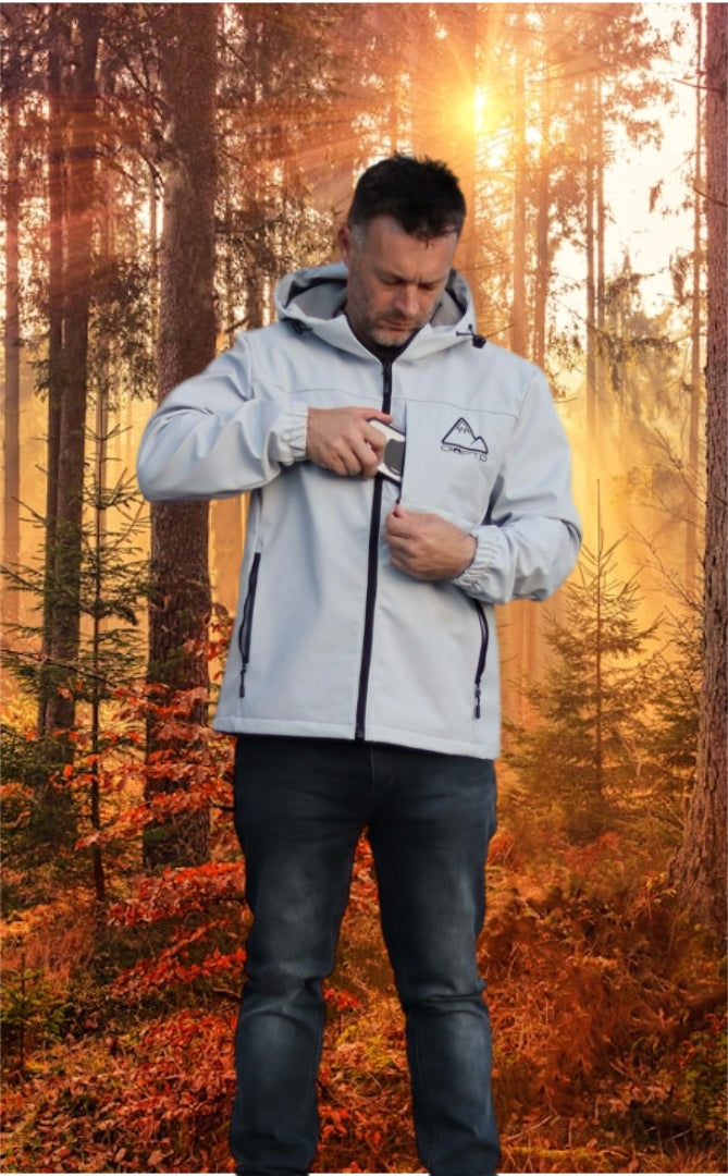 Man wearing a light gray crofto soft shell jacket in a forest during sunrise.