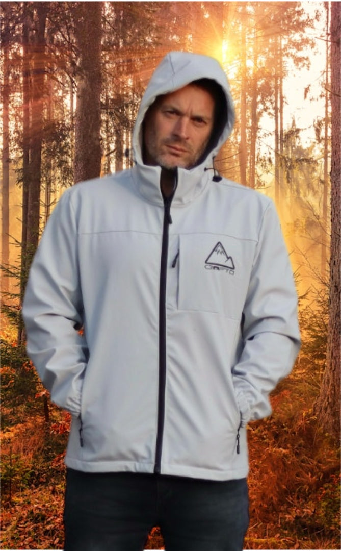 Man wearing a light gray crofto soft shell jacket in a forest during sunrise.