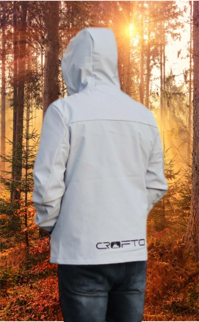 Man wearing a light gray crofto soft shell jacket in a forest during sunrise.