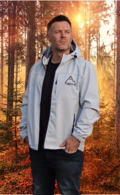 Man wearing a light gray crofto soft shell jacket in a forest during sunrise.
