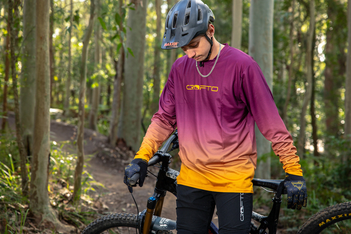 a man in a forest wearing a crofto fade mtb jersey in maroon and gold with black crofto amaroo mtb pants